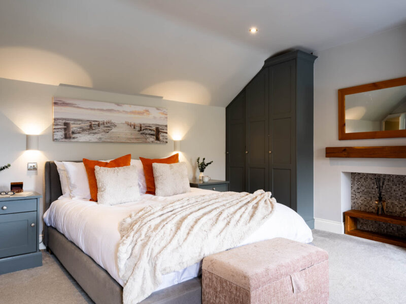 Malton Luxury Retreat: plush king-size bed with orange accents and coastal art.