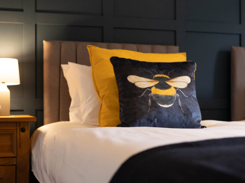 Malton Luxury Retreat: cozy bedroom with bumblebee cushion and bedside lamp.