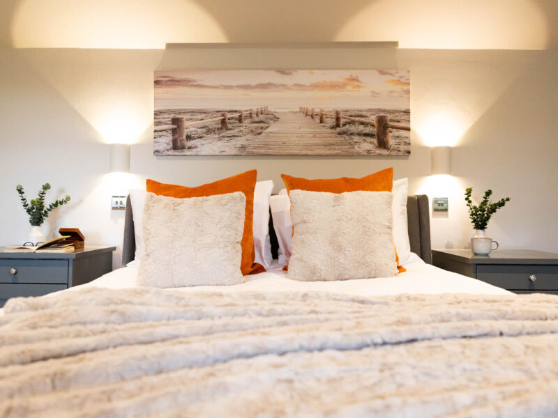 Luxury bedroom at Malton Retreat, featuring a plush bed and coastal artwork.
